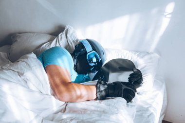 Snowboard kayak yapan bir adam Google ve miğferiyle yatakta.