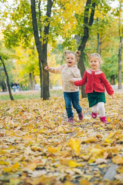 Duas meninas namoradas jogando no outono parque da cidade de mãos dadas — Fotografia de Stock