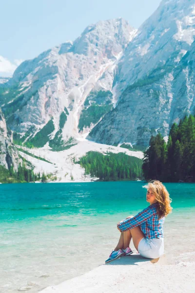 山の湖の夏の季節のビーチに座っている女性 — ストック写真