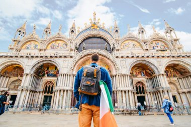 İtalyan bayrağı taşıyan bir adam Saint Marco Basilica 'ya bakıyor Venedik, İtalya