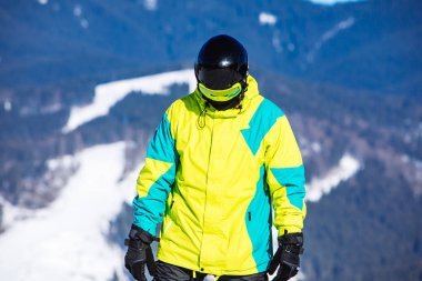 Tepenin tepesinde güneşli bir günde snowboard yapan bir adam.