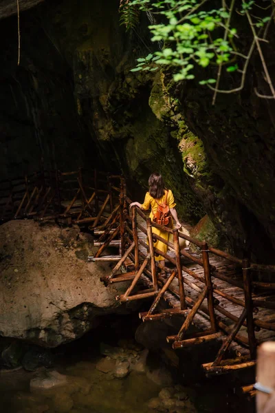 Gorgeous woman in yellow sundress looking at caves with river creek — Stock Photo, Image