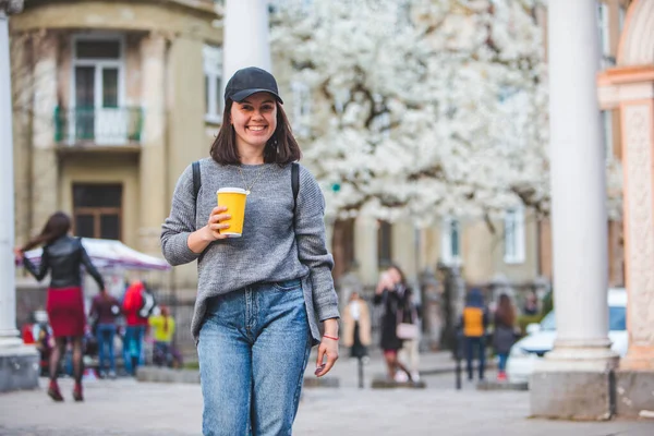 Jovem mulher elegante andando pela rua com xícara de café — Fotografia de Stock