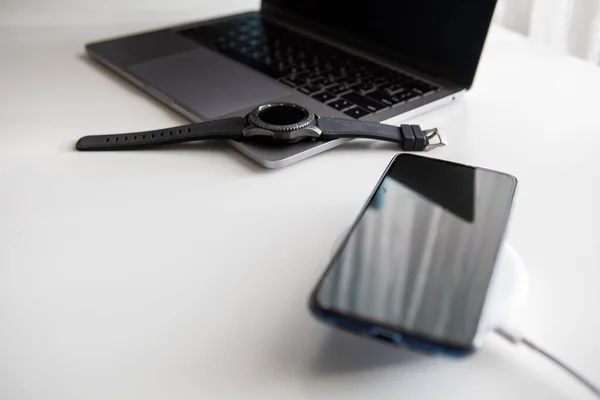 Ноутбук з смарт-годинником комп'ютерна миша і зарядка телефону на бездротовому зарядному пристрої — стокове фото