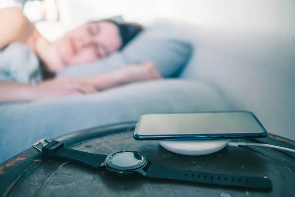 Mulher dormindo na cama celular carregando no carregador sem fio — Fotografia de Stock