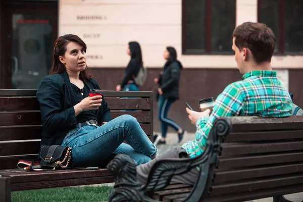 Sorrindo casal sentado no banco conversando uns com os outros beber café — Fotografia de Stock