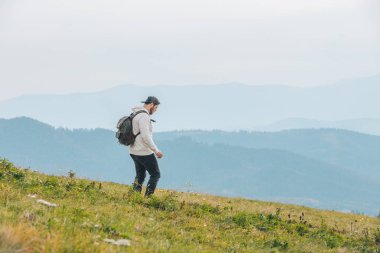 Sırt çantalı bir adam dağda yürüyüş yapıyor.