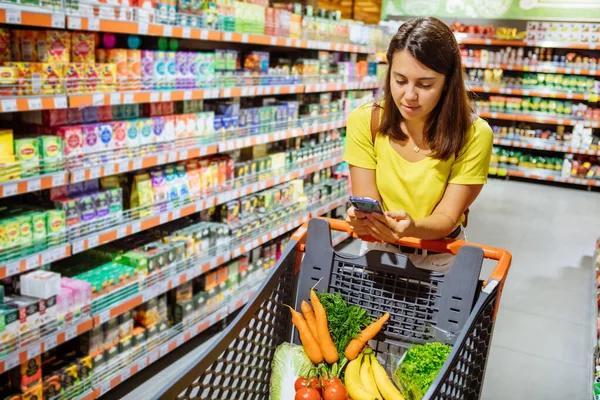 Frau macht Einkaufscheck, um Liste im Telefon zu kaufen — Stockfoto