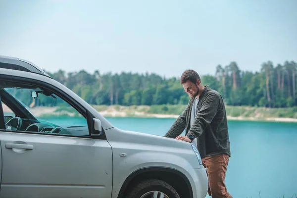 Homem do conceito do curso de carro que olha no homem no lago da capa do carro do SUV no fundo — Fotografia de Stock