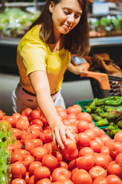 Kobieta wybiera czerwone pomidory z półki sklepowej sklep spożywczy — Zdjęcie stockowe