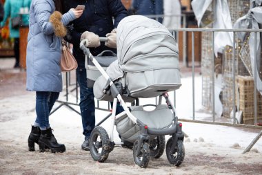 Genç bir aile babası ve çocuğuyla birlikte kış günü bebek arabasında dışarıda.