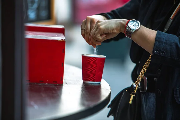 Mujer poner azúcar en taza de café de papel rojo —  Fotos de Stock