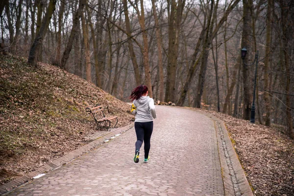 Donna che fa jogging correndo dal parco invernale — Foto Stock