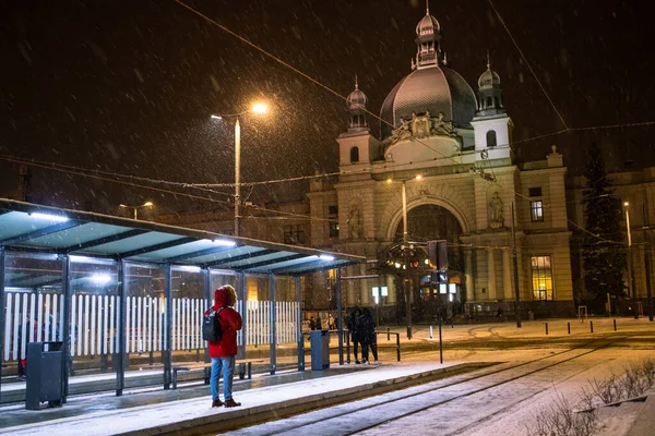 Człowiek w zimową śnieżną noc na dworcu kolejowym czeka na tramwaj — Zdjęcie stockowe