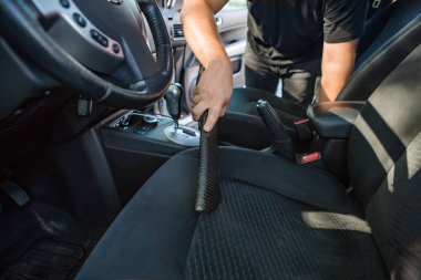 Adam elektrikli süpürge koltuklarıyla arabanın içini temizliyor.