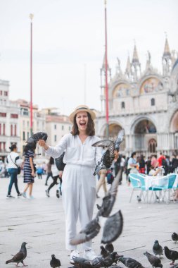 Beyaz şapkalı kadın Venice City Meydanı San Marco 'da güvercinlerle eğleniyor.