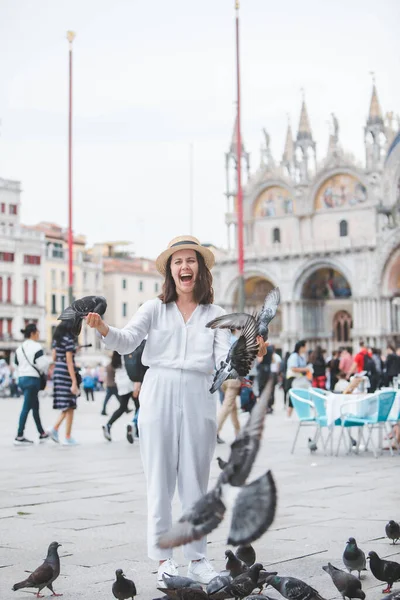 Beyaz şapkalı kadın Venice City Meydanı San Marco 'da güvercinlerle eğleniyor.