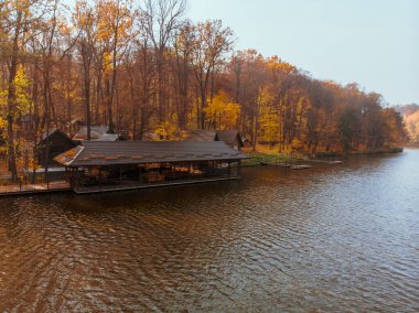 Göl kenarındaki sonbahar orman parkının havadan görüntüsü. İskeleler de bbq bölgesinde dinleniyor.
