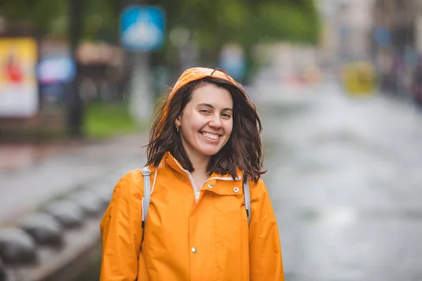 young pretty smiling woman portrait in raincoat with hood. overcast weather