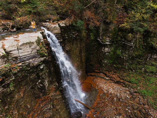 站在悬崖上看着瀑布欣赏秋天美景的女人 — 图库照片