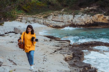 kadın deniz kenarında yürüyüş ve sarı yağmurluk manzara çekim. fırtına hava