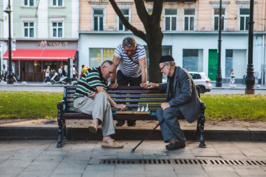 Lviv, Ukrayna - 3 Ağustos 2019 - Kentin bank parkında satranç oynayan yaşlılar. yaz zamanı