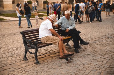 Lviv, Ukrayna - 18 Eylül 2018: İki yaşlı adam yazın şehir bankında açık havada satranç oynuyor.