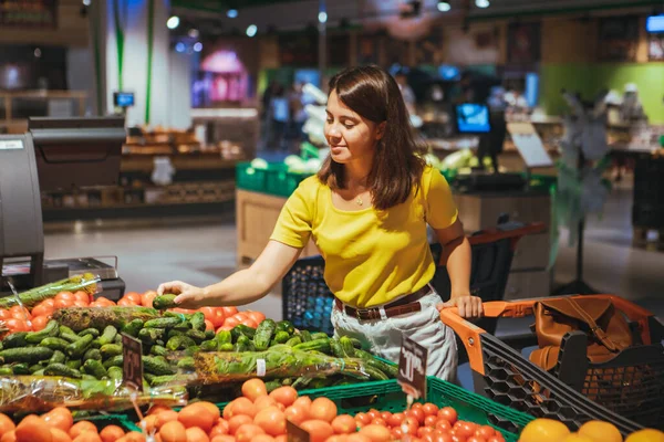 女人选择黄瓜从商店货架杂货店购物概念 — 图库照片