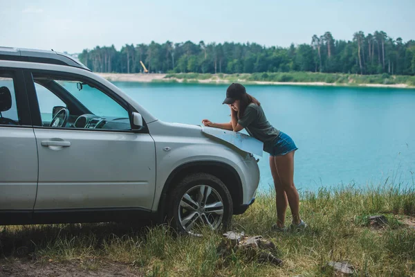 Žena Kontrola Mapou Suv Auto Kapota Jezero Modrou Vodou Pozadí — Stock fotografie