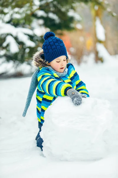 可愛い子が雪だるまを作ってる 大きな雪玉を転がす 冬のレジャー — ストック写真