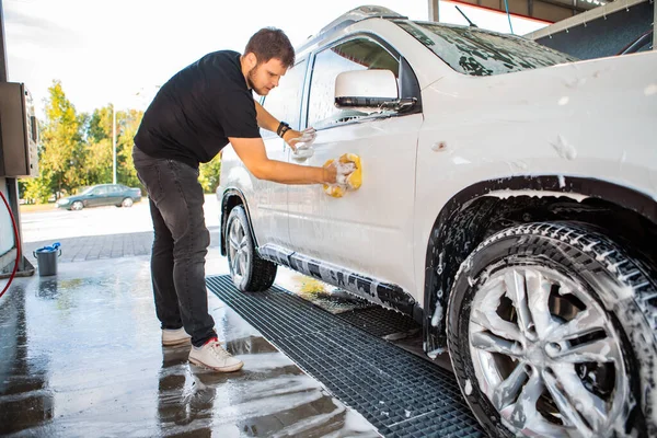 男人用黄色的海绵擦洗汽车 洗车的概念 复制空间 — 图库照片