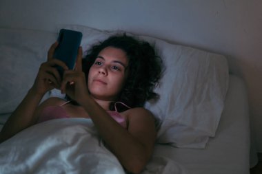 Gece internet bağımlılığında cep telefonu olan genç bir kadın.