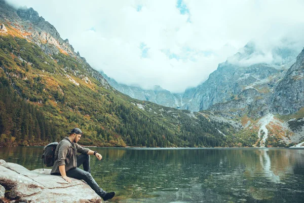 Muž Sedí Skále Před Jezerem Horách Těší Výhledu Turistiku — Stock fotografie