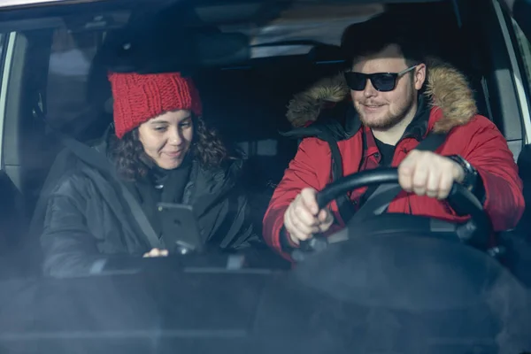 couple in car in winter outfit driving and talking navigation on phone rent a car