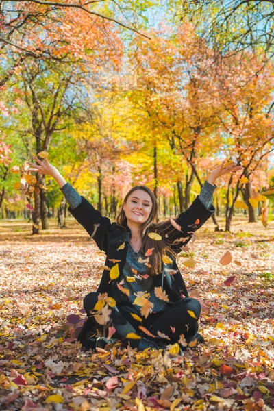 Młoda Ładna Kobieta Bawi Się Żółtymi Jesiennymi Liśćmi Parku Miejskim — Zdjęcie stockowe