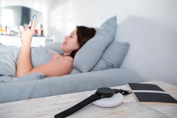 Woman Surfing Internet Cellphone Laying Bed Smart Watch Wireless Charger — Stock Photo, Image