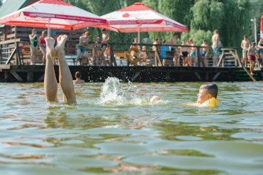 Şişme kollarıyla gölde yüzen küçük çocuk yaz gölünü destekliyor.