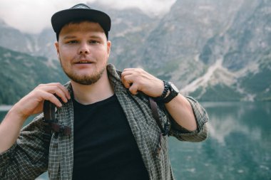 Dağlarda, gölün önünde yürüyen güçlü bir adamın portresi.