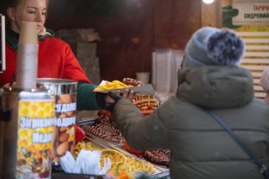 Lviv, Ukraine - January 4, 2019: woman service street food to a man. outdoors fair fest