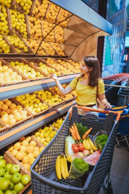 süpermarket mağaza raf alışveriş konseptinden portakal alan kadın