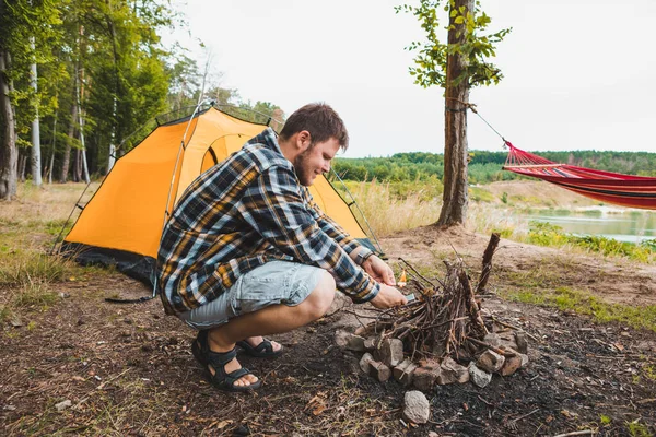 Jonge Sterke Man Steken Een Vuur Camping Gele Tent Achtergrond — Stockfoto