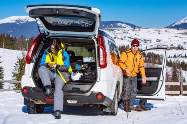 Cip arabasının yanındaki kadın sandık dolusu kayak malzemesi ve bot değiştiren snowboard malzemesi açtı. kış yolculuğu