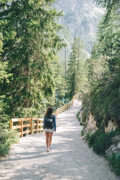 happy woman with backpack walking by trail in national park mountains on background. summer time