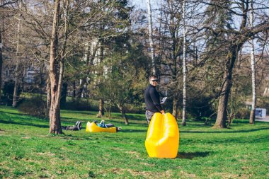 kitap okumak için yer sarı şişme yatak ile yürüyen adam. açık havada dinlenme süresi