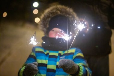 Geceleri küçük şirin bir çocuk. Kış şehri parkında. Paltosu kalın ve maytaplı.
