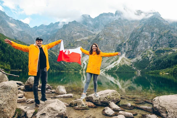 폴란드 국기를 노란색 비옷을 부부가 해변에 — 스톡 사진