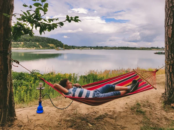 Pria Berbaring Tempat Tidur Gantung Merokok Hookah Melihat Danau Waktu — Stok Foto