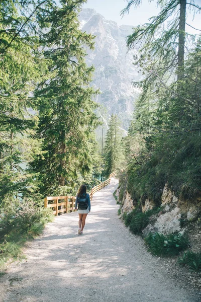 happy woman with backpack walking by trail in national park mountains on background. summer time