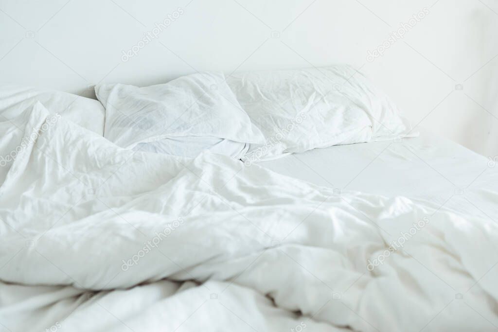 bed with white sheets close up bright morning light copy space