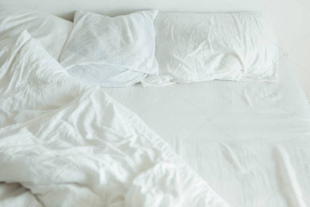 bed with white sheets close up bright morning light copy space